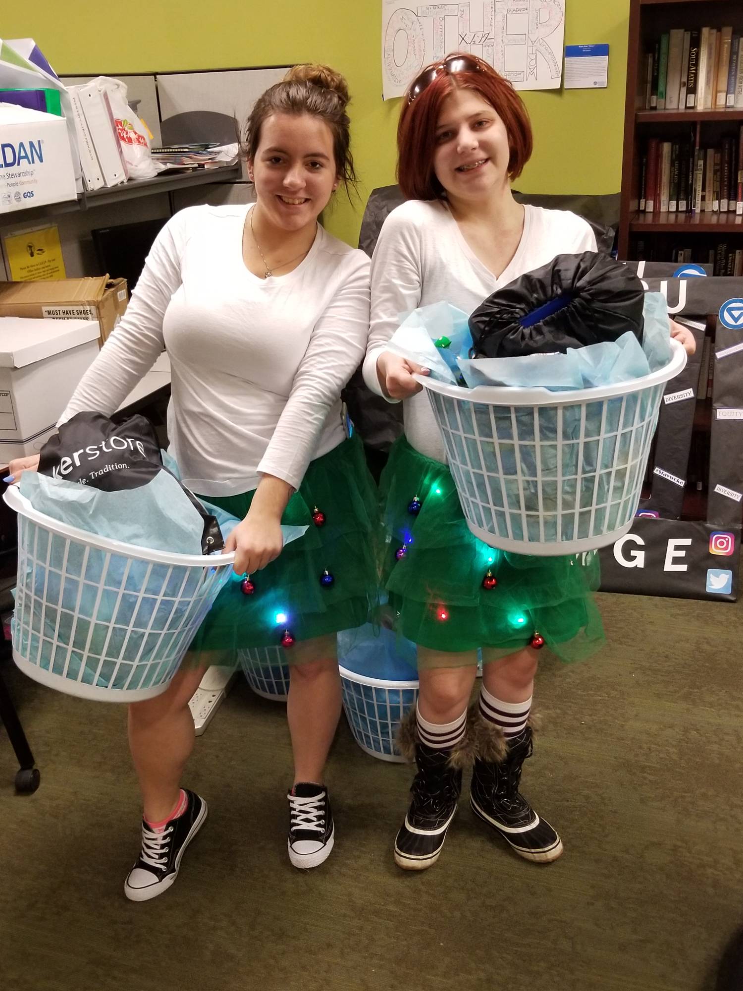 Two students smiling while holding laundry baskets